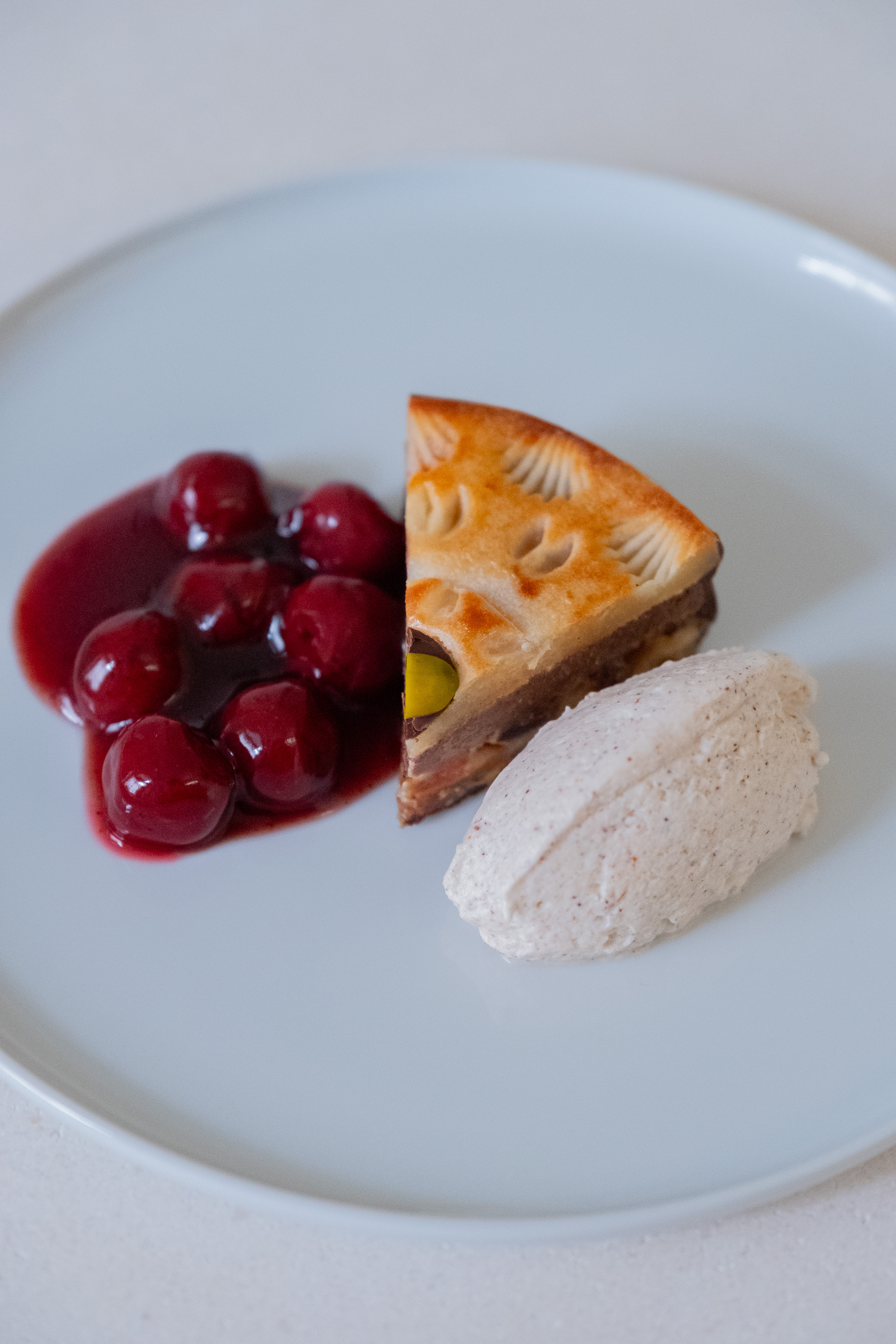 Stimmungsbild: Sawade Torten Stück mit Glühweinkirschen und Zimtsahne auf weißem Teller angerichtet